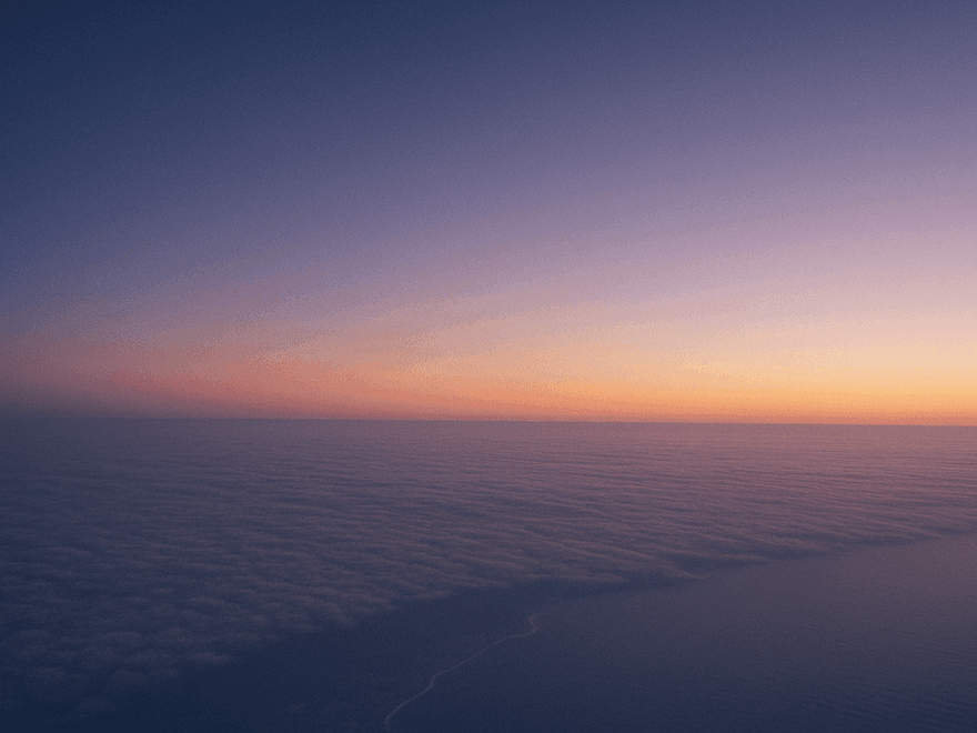 Dawn above an unbroken floor of cloud, a warm band of light along a curved horizon